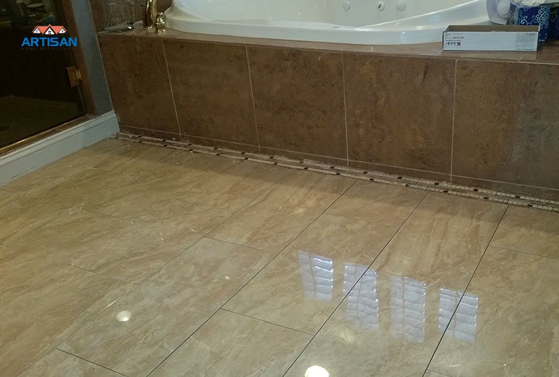 A polished stone floor and tub surround in a finished bathroom