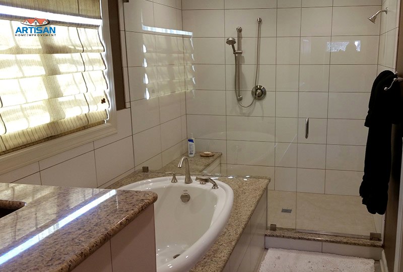 A tiled tub and shower beside a stone topped vanity