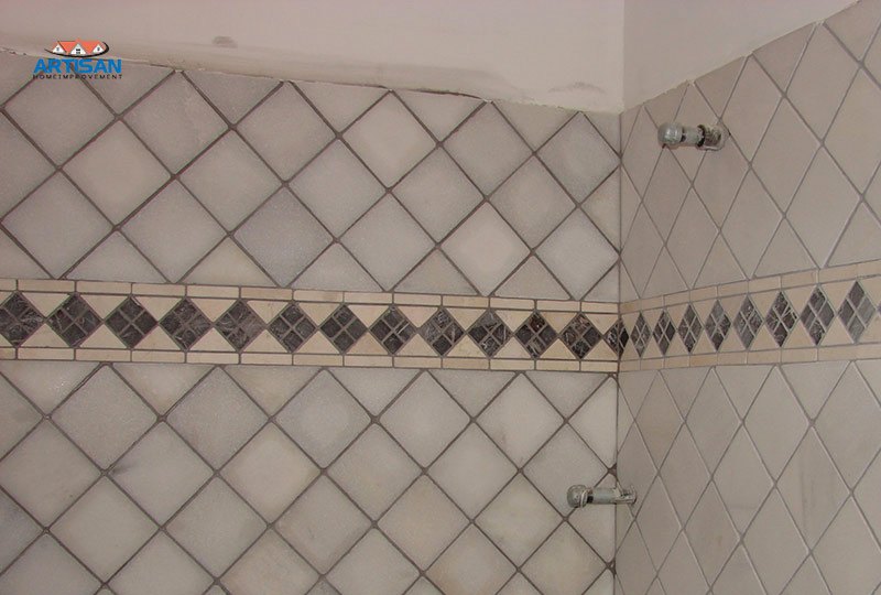 A diamond pattern tile shower wall with a decorative inset border