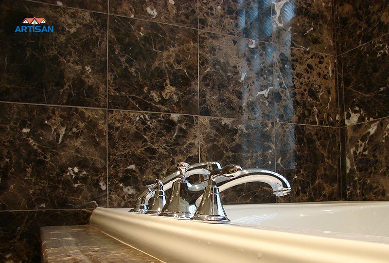 A dark marble tub surround with polished fittings